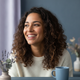 Close-up portrait of a happy woman with a genuine smile, looking slightly off-camera. The background is softly blurred with m